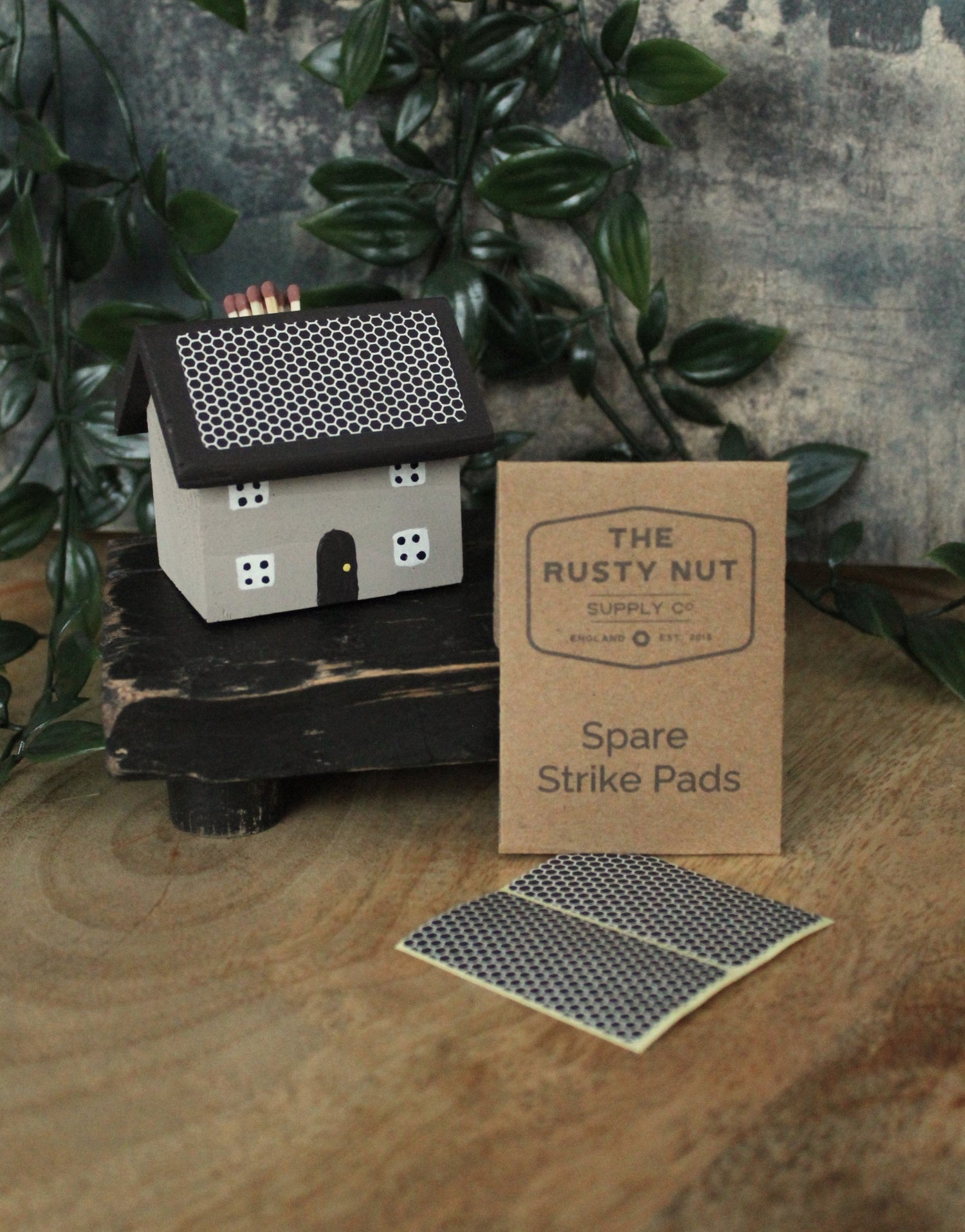 Cute hand painted wooden house match holder, with brown spares envelope and two spare match strike pads. Sitting on a vintage style wooded table