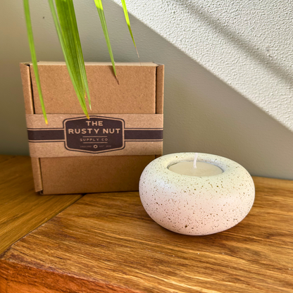 Cast stone Sanctuary tealight holder with lit tealight displayed beside The Rusty Nut Supply Co branded gift box