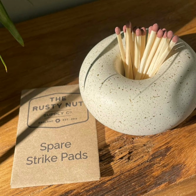 Matches in a stone holder with spare strike pads on a wooden surface