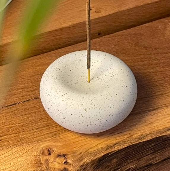 Incense stick burning on a white stone holder on a wooden surface