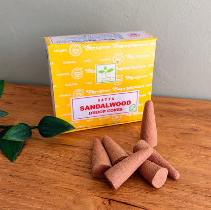 Satya Sandalwood Dhoop Cones box with incense cones stacked in front, on a wooden table