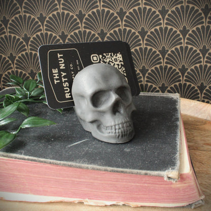 grey cast stone skull business card holder. Sitting on a vinage book with datk background