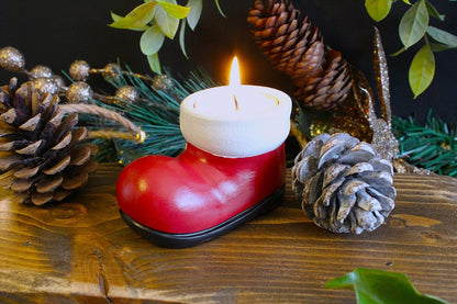 Santa boot tea light holder glowing among pine cones